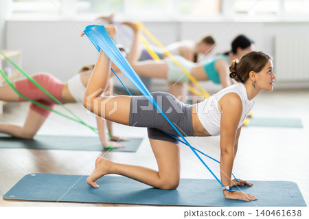 Young girl practicing back leg lift with band standing on knees 140461638