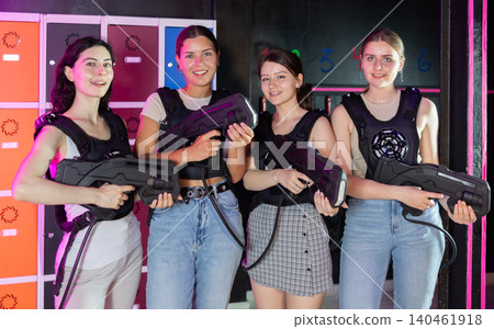 Four cheerful and happy girls pose in locker room before laser tag match. Four cheerful and happy girls pose in locker room before laser tag match. 140461918
