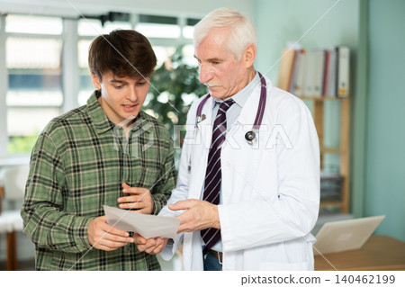 Senior doctor discusses medical tests with guy in clinic Senior doctor discusses medical tests with guy in clinic 140462199