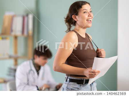 Happy young girl patient leaving medical office after doctor appointment holding prescription in hands in medical center Happy young girl patient leaving medical office after doctor appointment holding prescription in hands in medical center 140462369