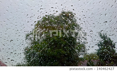 Clear Raindrops on Glass Window with Green Foliage Bokeh Clear Raindrops on Glass Window with Green Foliage Bokeh 140462427