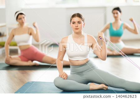 Group of young women exercising their arm muscles using resistance bands Group of young women exercising their arm muscles using resistance bands 140462623