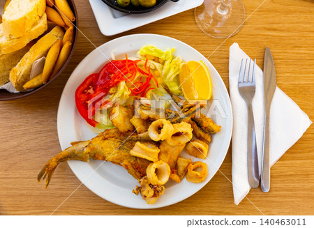 Fried seafood delicacies with fresh vegetables and lemon 140463011