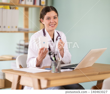 woman, a doctor in the office near the laptop, she is holding vitamins for pregnant women woman, a doctor in the office near the laptop, she is holding vitamins for pregnant women 140463027