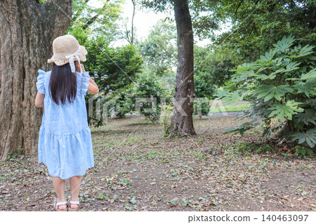 A girl's back as she enjoys playing with soap bubbles in the park. 140463097
