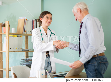Elderly man thanks female doctor and shakes her hand Elderly man thanks female doctor and shakes her hand 140463196