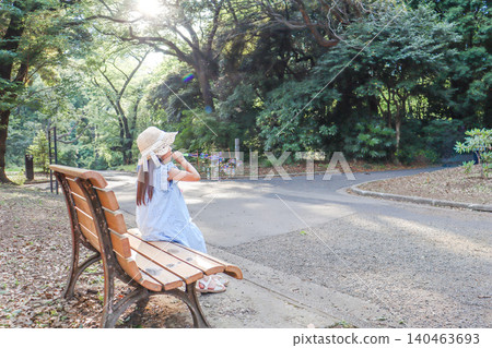 陽光透過樹葉灑在公園長椅上,一個小女孩正開心地玩著肥皂泡。 陽光透過樹葉灑在公園長椅上,一個小女孩正開心地玩著肥皂泡。 140463693
