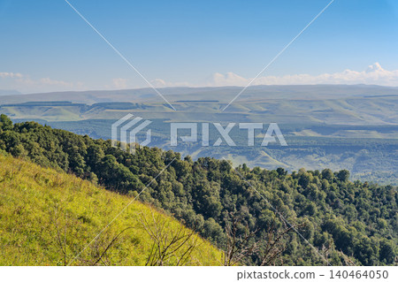 Panoramic view of the green valley and the snowy peak of Mount Elbrus on the horizon against the blue sky on a sunny clear morning in Kislovodsk Stavropol territory, Russia Panoramic view of the green valley and the snowy peak of Mount Elbrus on the horizon against the blue sky on a sunny clear morning in Kislovodsk Stavropol territory, Russia 140464050