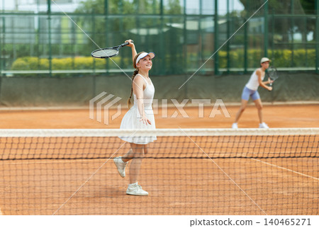 Woman playing tennis against female opponent on tennis court Woman playing tennis against female opponent on tennis court 140465271