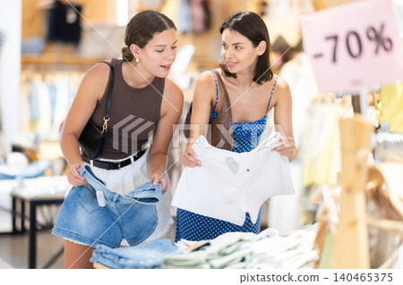 Two girls customer chooses shorts in store Two girls customer chooses shorts in store 140465375