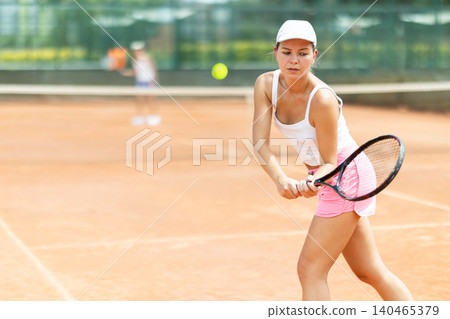 Female athlete plays tennis on open court Female athlete plays tennis on open court 140465379