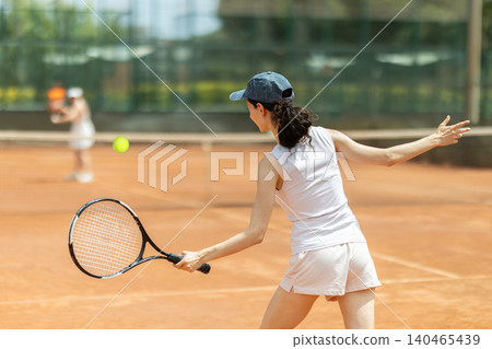 Concentrated sporty girl with tennis racquet and ball in her hands standing and ready to play match standing Concentrated sporty girl with tennis racquet and ball in her hands standing and ready to play match standing 140465439