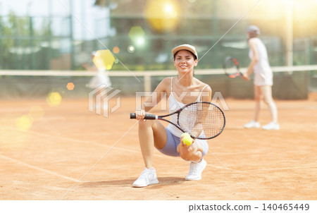 Woman in sportswear against backdrop of outdoor tennis court Woman in sportswear against backdrop of outdoor tennis court 140465449