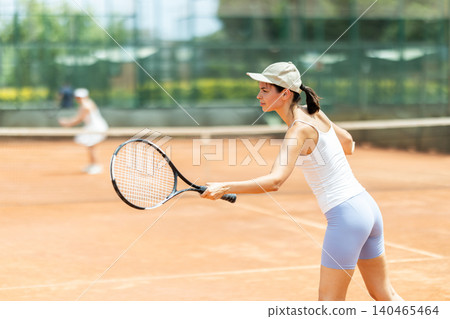 Concentrated sporty girl with tennis racquet and ball in her hands standing and ready to play match standing Concentrated sporty girl with tennis racquet and ball in her hands standing and ready to play match standing 140465464