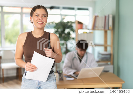 Happy young girl holding successful test results in clinical office 140465493