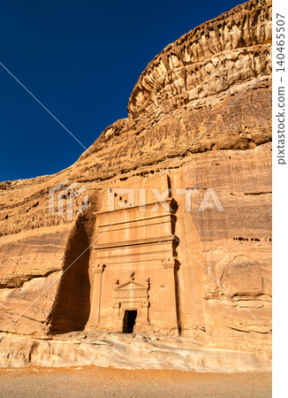 A majestic Nabataean tomb carved directly into the red sandstone mountains of Hegra in Al Ula, Saudi Arabia, a UNESCO World Heritage site known for its ancient Nabataean architecture. A majestic Nabataean tomb carved directly into the red sandstone mountains of Hegra in Al Ula, Saudi Arabia, a UNESCO World Heritage site known for its ancient Nabataean architecture. 140465507