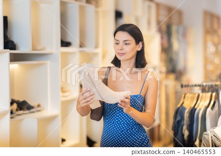 Young woman standing in a clothing store and choosing shoes 140465553