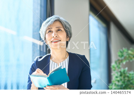 一位女士打開筆記本,陷入沉思。 一位女士打開筆記本,陷入沉思。 140465574