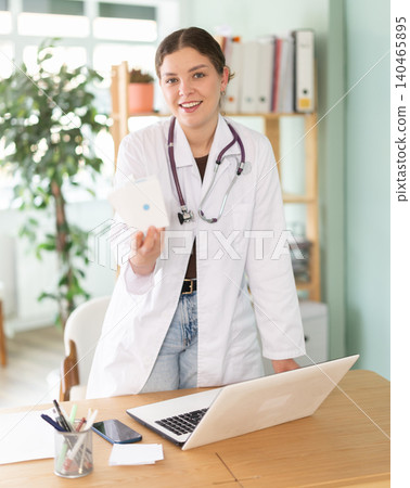 woman, a doctor in the office near the laptop, she is holding vitamins for pregnant women woman, a doctor in the office near the laptop, she is holding vitamins for pregnant women 140465895
