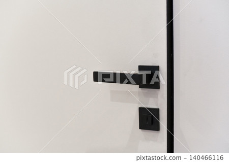 A close view shows a simple black door handle and switch on a light wall. This highlights the style chosen for the home renovation work. A close view shows a simple black door handle and switch on a light wall. This highlights the style chosen for the home renovation work. 140466116