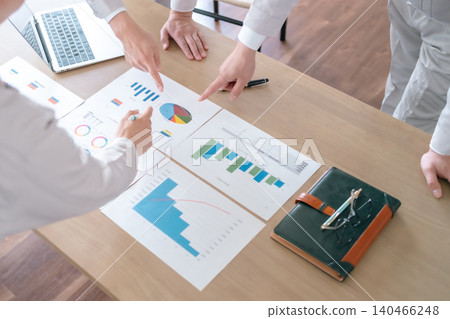 一位身著職業裝的商人正在會議上指著圖表。 140466248