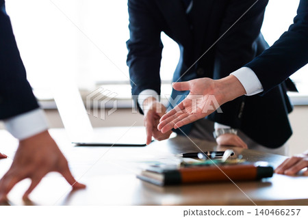 A close-up of the hands of business people pointing at the documents they have presented during a meeting. A close-up of the hands of business people pointing at the documents they have presented during a meeting. 140466257