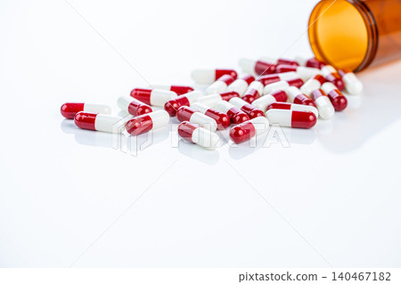 Red and white prescription capsules spilling from a plastic container. Regulated pharmaceutical drugs. Emphasizing safety standards, medication efficacy, and patient well-being in healthcare industry. Red and white prescription capsules spilling from a plastic container. Regulated pharmaceutical drugs. Emphasizing safety standards, medication efficacy, and patient well-being in healthcare industry. 140467182