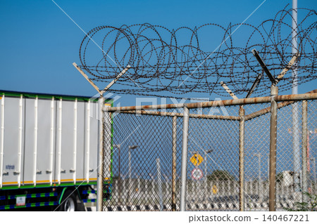 Sharp barbed wire border fence blocking access. Surveillance, conflict, and restricted freedoms, reflecting geopolitical divisions and the impact of immigration policies on displaced people. 140467221