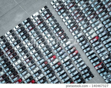 Aerial view of new cars stock at a large factory parking lot. Automotive industry, logistics operations, and vehicle storage for import and export. Key role in the global car market supply chain. Aerial view of new cars stock at a large factory parking lot. Automotive industry, logistics operations, and vehicle storage for import and export. Key role in the global car market supply chain. 140467327
