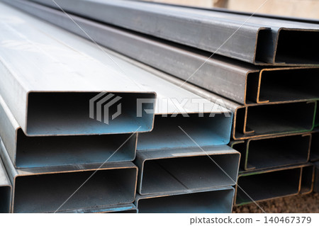 Industrial warehouse stock of rectangular metal pipes for building and construction supplies. Stack of steel pipes. Iron materials for construction and infrastructure projects. Steel tubing storage. Industrial warehouse stock of rectangular metal pipes for building and construction supplies. Stack of steel pipes. Iron materials for construction and infrastructure projects. Steel tubing storage. 140467379