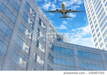 Airplane flying in the sky above modern sustainable glass office building. Exterior skyscraper green glass building. Business travel. Aviation business. Air logistics. Cargo plane. Departure flight. 140467593