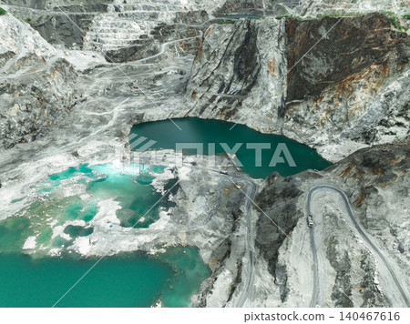 Large limestone quarry operation. Industrial trucks working at open pit mining site with striking turquoise water. Resource extraction process. Mining operation in limestone quarry. Industrial scale. Large limestone quarry operation. Industrial trucks working at open pit mining site with striking turquoise water. Resource extraction process. Mining operation in limestone quarry. Industrial scale. 140467616