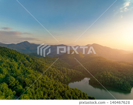 Beautiful landscape of green mountains and lake in the morning with sunrise sky. Nature landscape. Watershed forest. Water and forest sustainability concept. Aerial view of mountain with green trees. Beautiful landscape of green mountains and lake in the morning with sunrise sky. Nature landscape. Watershed forest. Water and forest sustainability concept. Aerial view of mountain with green trees. 140467628