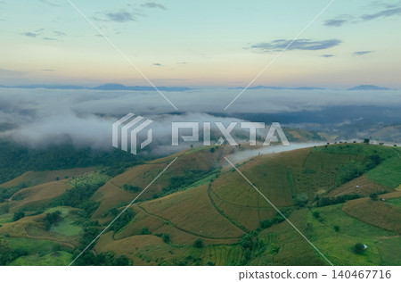 Beautiful green mountain landscape with morning sunrise sky and fog. Aerial view of green trees and corn field on the mountain forests and fog in winter. Nature scene. Green environment background. Beautiful green mountain landscape with morning sunrise sky and fog. Aerial view of green trees and corn field on the mountain forests and fog in winter. Nature scene. Green environment background. 140467716