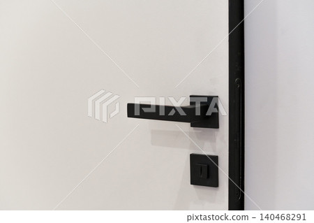 A door with a black handle and a matching lock is installed in a home renovation, highlighting a clean and updated entryway. A door with a black handle and a matching lock is installed in a home renovation, highlighting a clean and updated entryway. 140468291