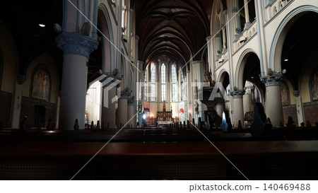 Inside a grand Catholic church with dark wooden pews Inside a grand Catholic church with dark wooden pews 140469488