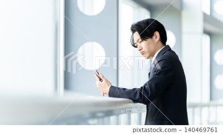 A businessman looking at his smartphone and agonizing over something. A businessman looking at his smartphone and agonizing over something. 140469761