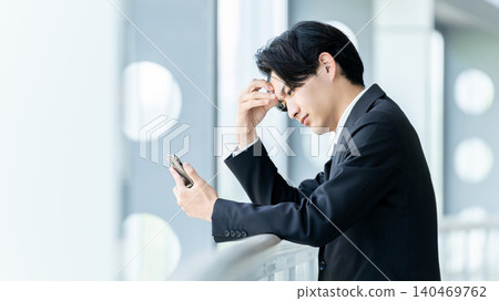一位商人看著他的智慧型手機,為某件事苦惱不已。 一位商人看著他的智慧型手機,為某件事苦惱不已。 140469762