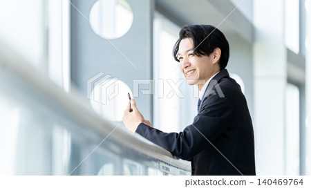 Smiling male businessman using a smartphone Smiling male businessman using a smartphone 140469764