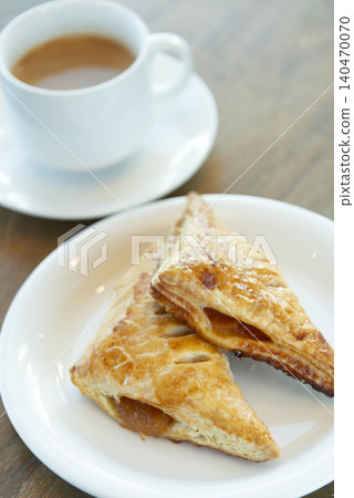 A café set consisting of a triangular apple pie served on a white plate and a cup of coffee. A café set consisting of a triangular apple pie served on a white plate and a cup of coffee. 140470070