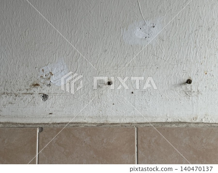 Old wall texture with screw holes, peeling paint and stains close-up 140470137