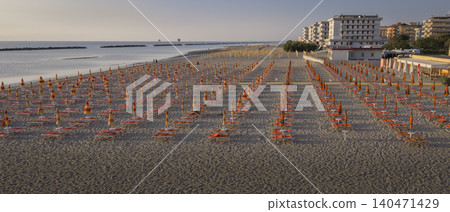 Aerial shot of sandy beach with umbrellas and gazebos.Summer vacation concept.Lido Adriano town,Adriatic coast, Emilia Romagna,Italy. Aerial shot of sandy beach with umbrellas and gazebos.Summer vacation concept.Lido Adriano town,Adriatic coast, Emilia Romagna,Italy. 140471429
