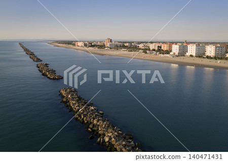 Drone shot of sandy beach with umbrellas and gazebos.Summer vacation concept.Lido Adriano town,Adriatic coast, Emilia Romagna,Italy. Drone shot of sandy beach with umbrellas and gazebos.Summer vacation concept.Lido Adriano town,Adriatic coast, Emilia Romagna,Italy. 140471431