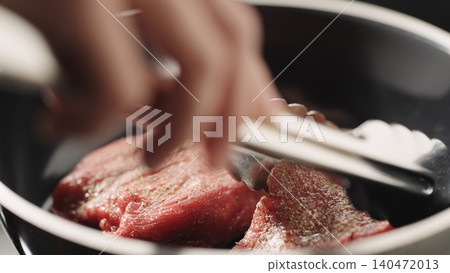 Close-up of raw steak fillet in black frying pan under soft directional light 140472013