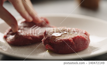 Close-up of two seasoned raw beef fillets on white plate 140472149
