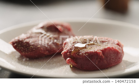Close-up of two seasoned raw beef fillets on white plate 140472158