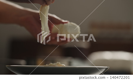Hand adding mozzarella cheese over penne pasta on dark plate Hand adding mozzarella cheese over penne pasta on dark plate 140472201