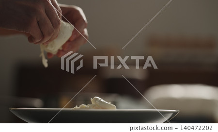 Hand adding mozzarella cheese over penne pasta on dark plate Hand adding mozzarella cheese over penne pasta on dark plate 140472202