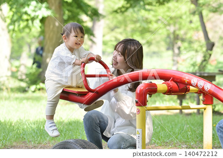 A mother and daughter enjoying a seesaw in the park. A mother and daughter enjoying a seesaw in the park. 140472212