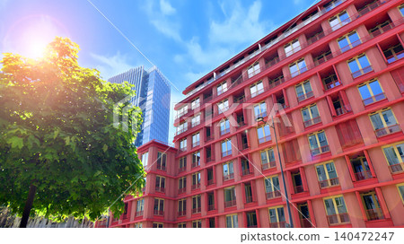 View of an modern apartment building standing next to a new modern office building with a glass facade. View of an modern apartment building standing next to a new modern office building with a glass facade. 140472247